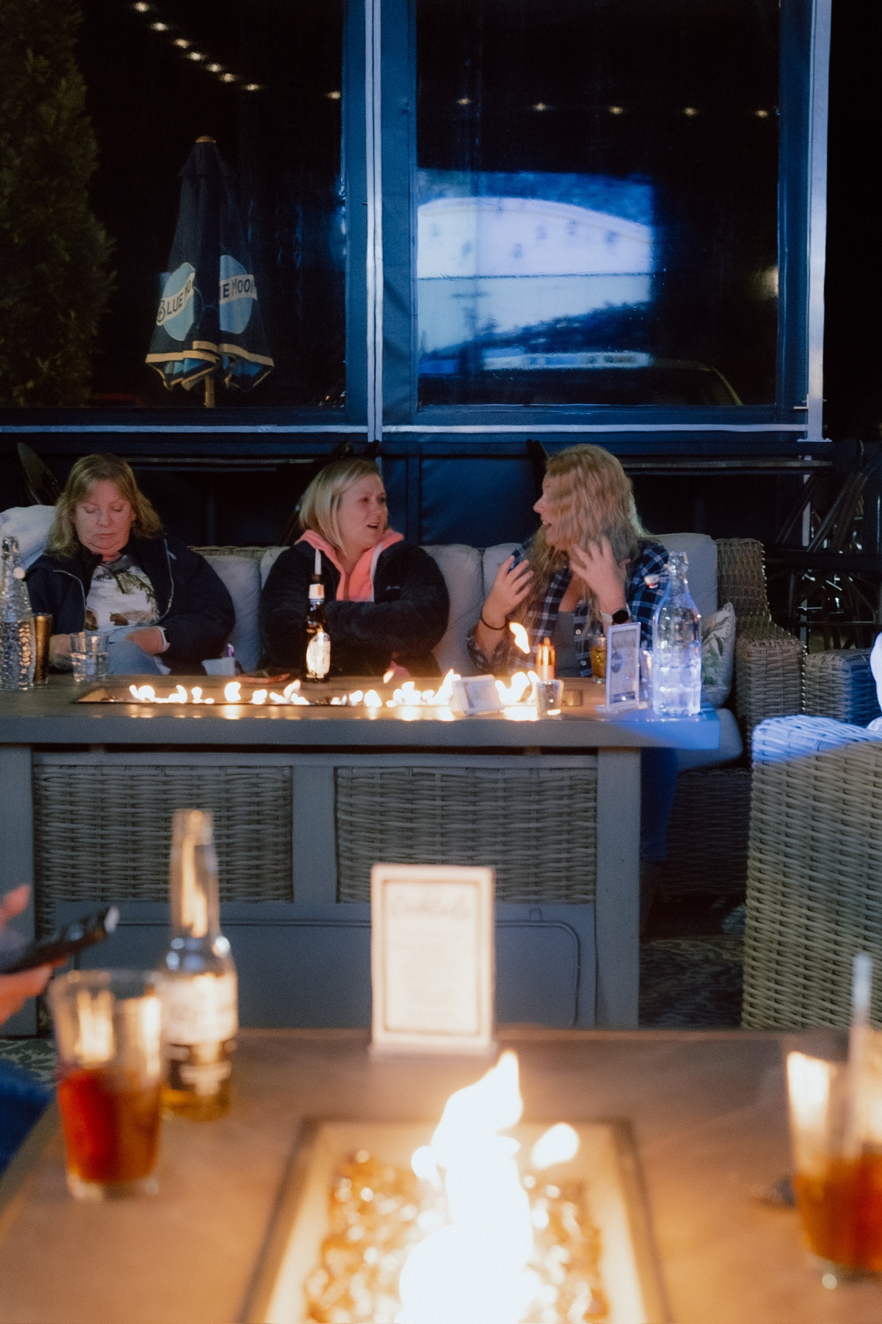 Friends gathered around the patio firepit at night
